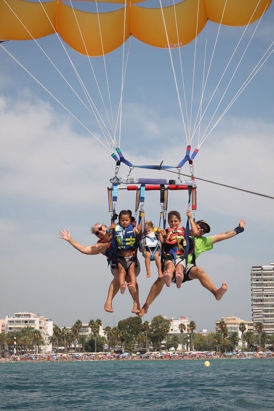 un grupo de personas está volando en un paracaídas en el océano