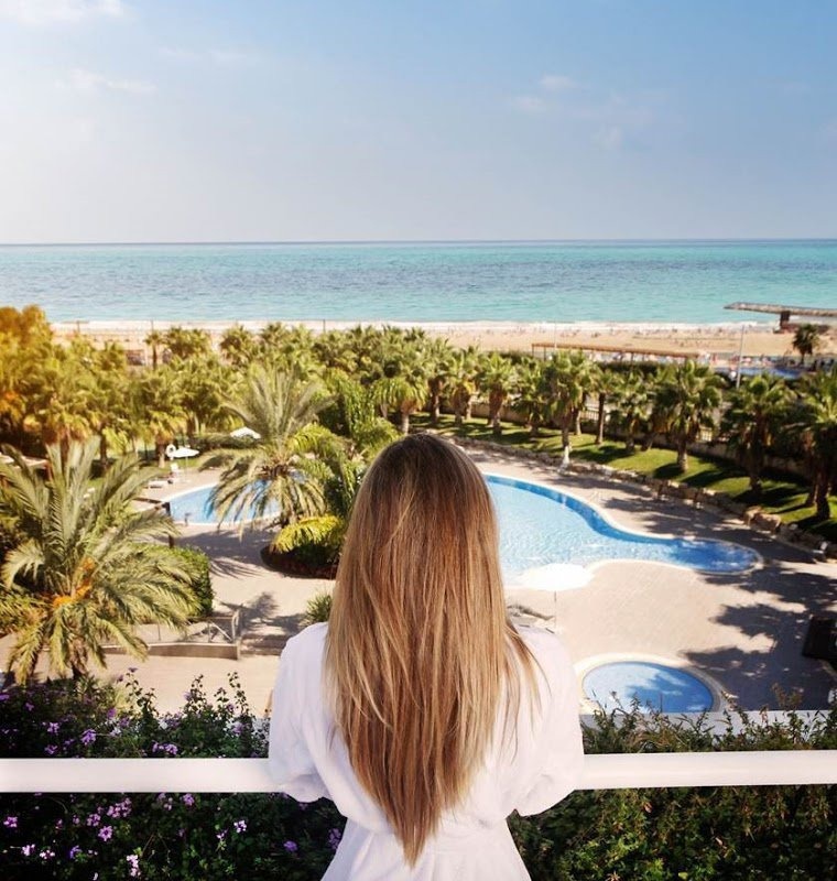 Jeune fille se penchant sur le balcon en regardant l'hôtel Gran Palas Experience à la Costa Daurada