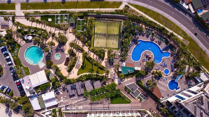 an aerial view of a large swimming pool surrounded by palm trees