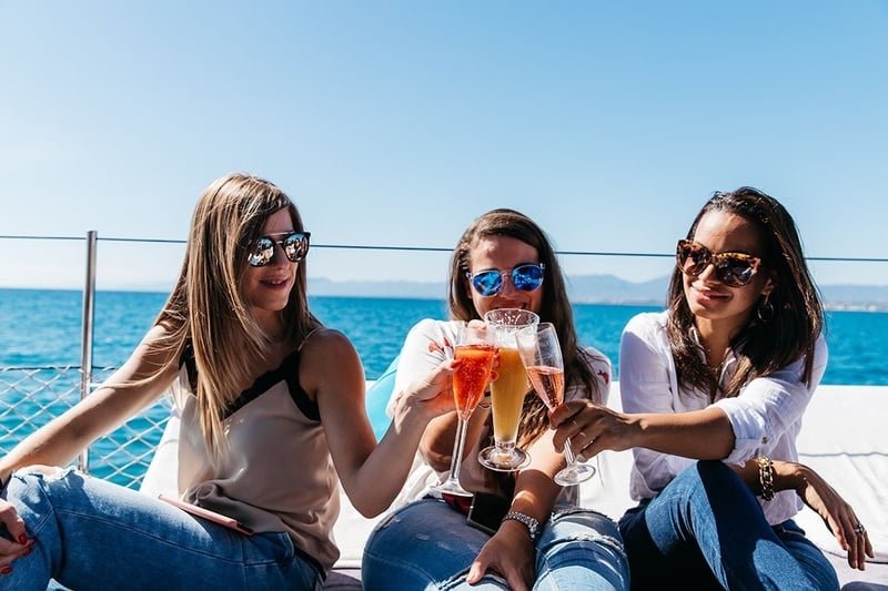 tres mujeres brindan con copas de champán en un barco
