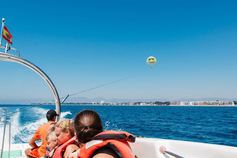 un grupo de personas en un barco miran un paracaídas en el océano