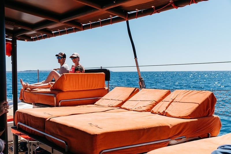 un hombre y una mujer están sentados en una cama naranja en un barco