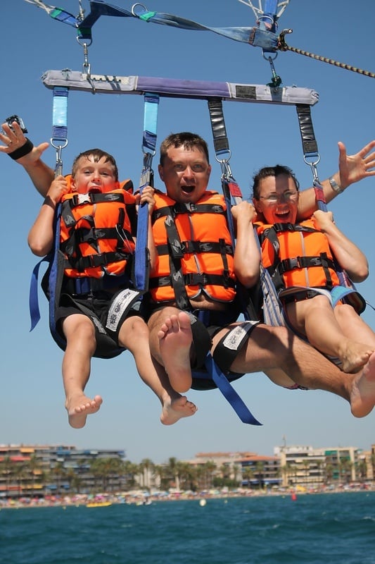 un hombre y dos niños parasailing en el océano