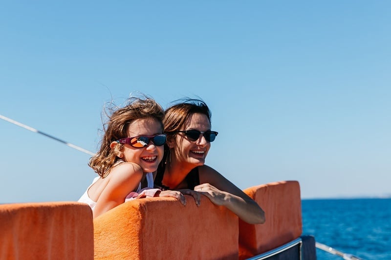 una mujer y una niña con gafas de sol miran hacia el océano
