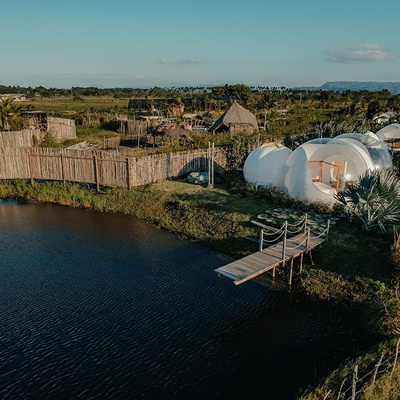 a wooden bridge over a body of water leads to a bubble house