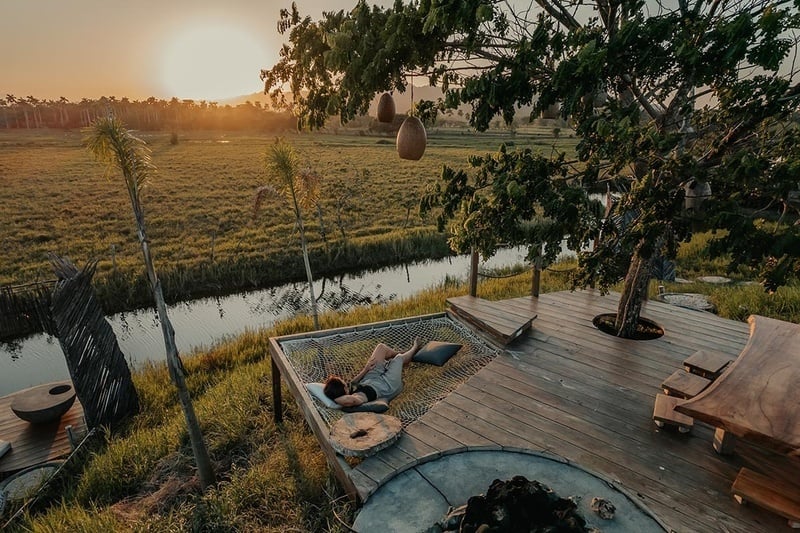 a person laying in a hammock overlooking a river