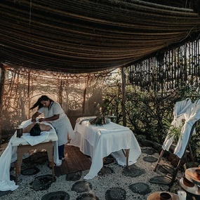 a woman is giving a man a massage under a canopy