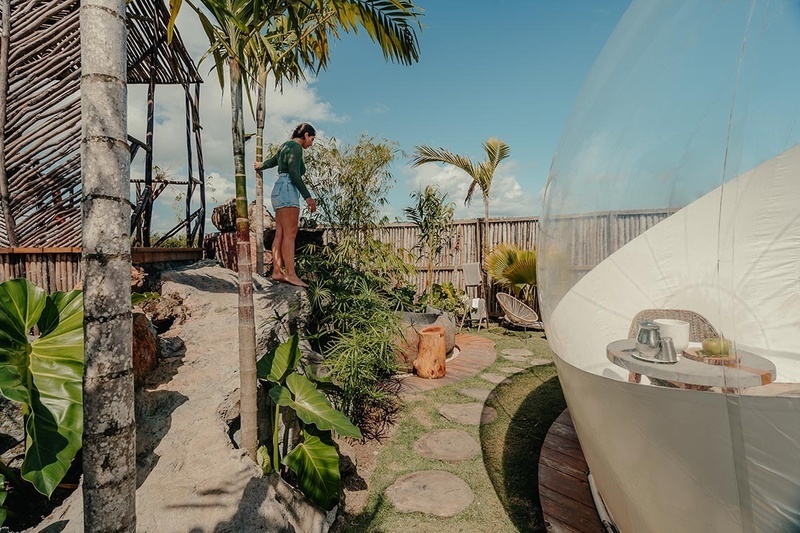 a woman stands on a rock near a bubble bathtub