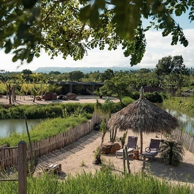 a thatched hut sits near a body of water