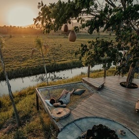 a person laying in a hammock overlooking a river