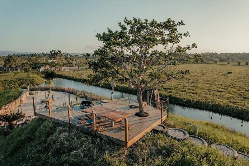 a wooden deck overlooking a river with a table and hammock