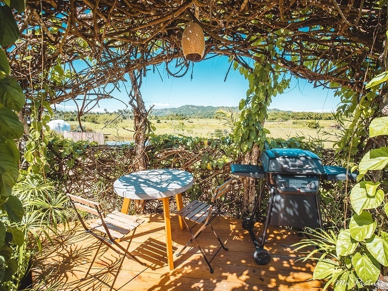 a table and chairs under a canopy with a grill