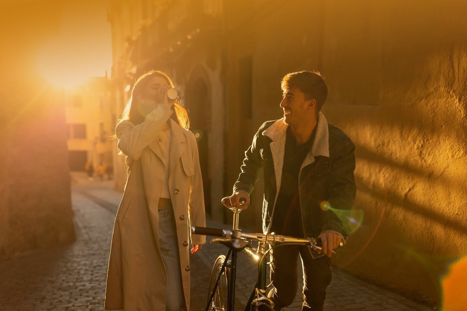 un hombre y una mujer caminan por una calle con una bicicleta