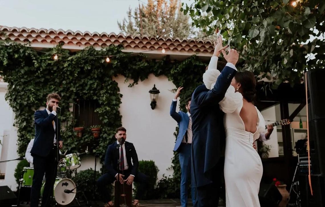 una novia y un novio bailan frente a un grupo de músicos