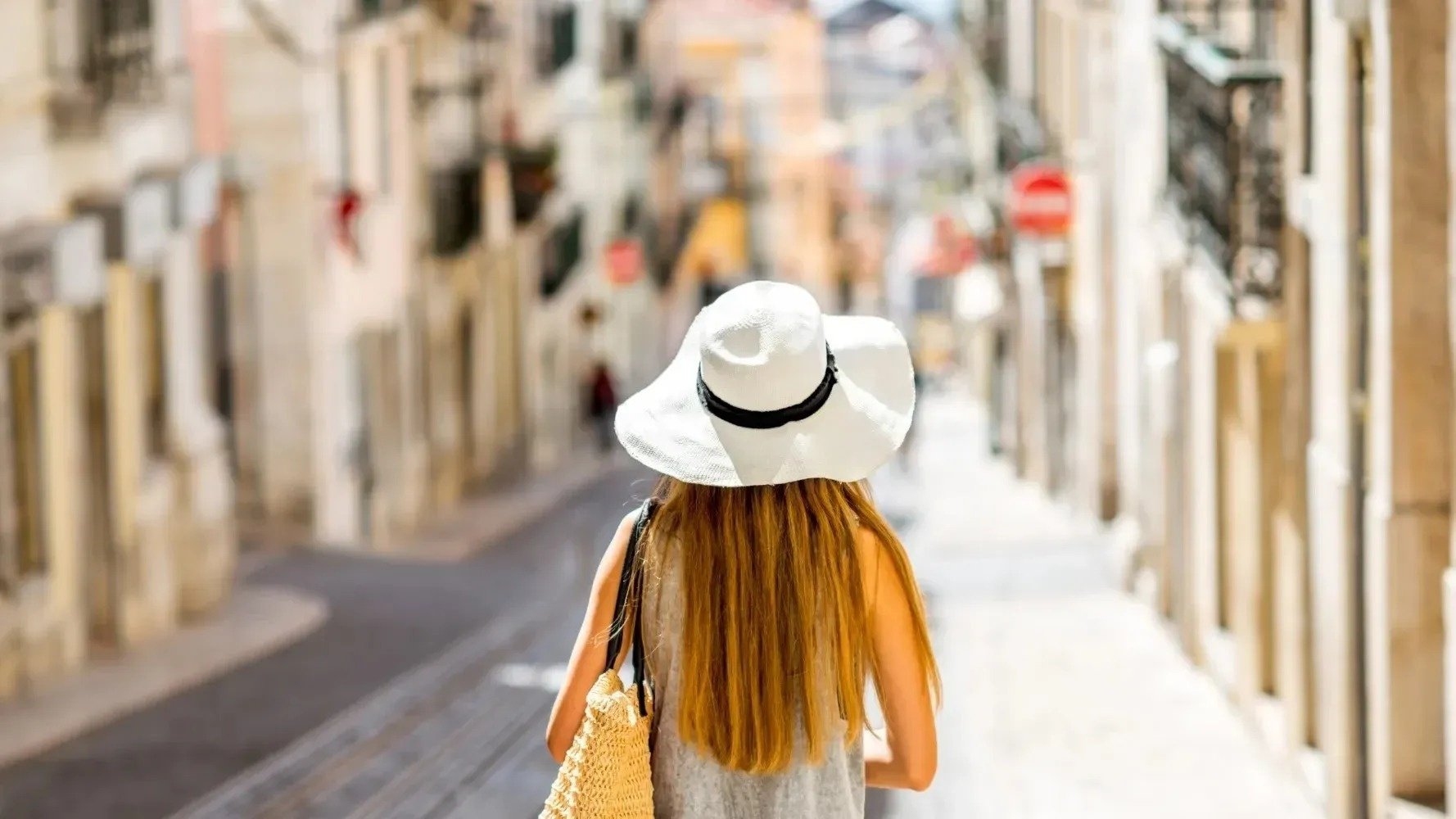 una mujer con sombrero camina por una calle estrecha