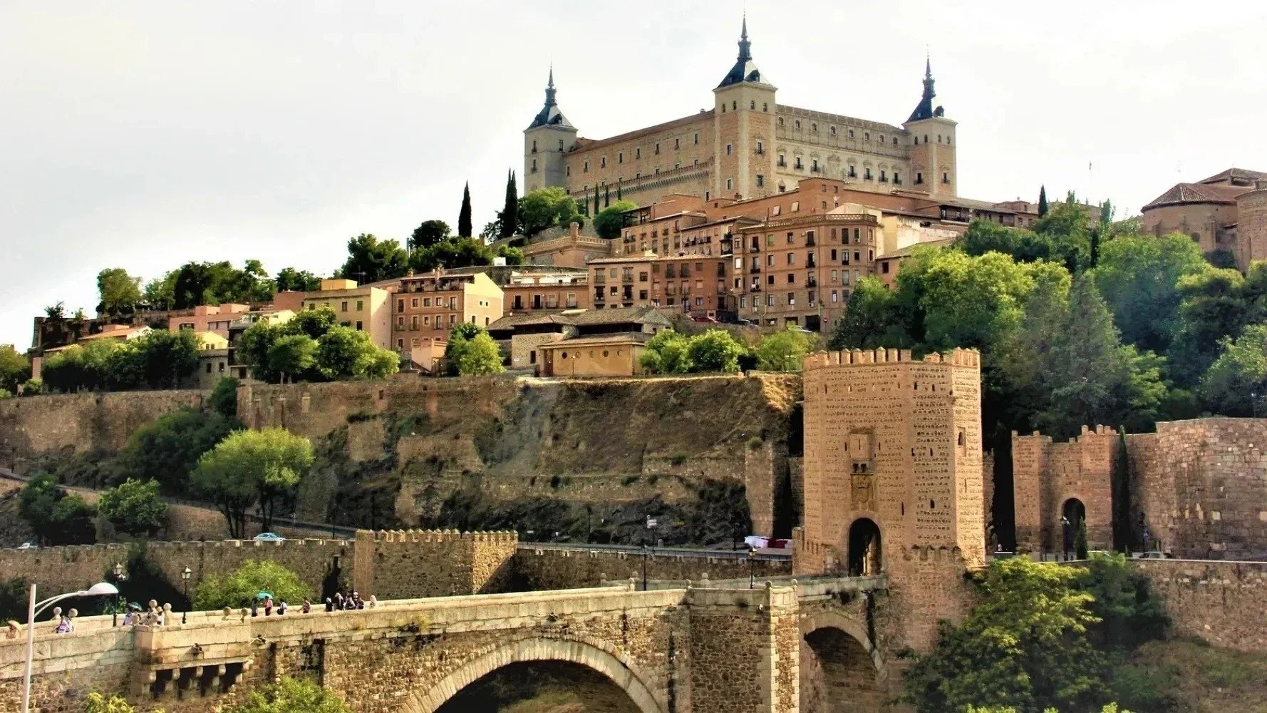 un puente que conduce a una ciudad con un castillo en el fondo