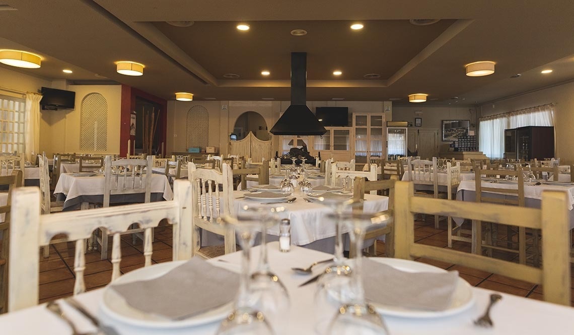 un restaurante lleno de mesas y sillas con platos y copas