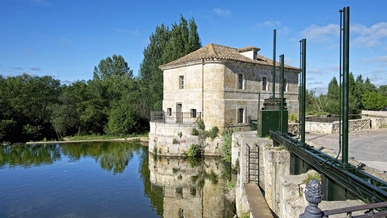 Historic Hacienda Zorita Wine Hotel on a river, featuring stone architecture and lush greenery.