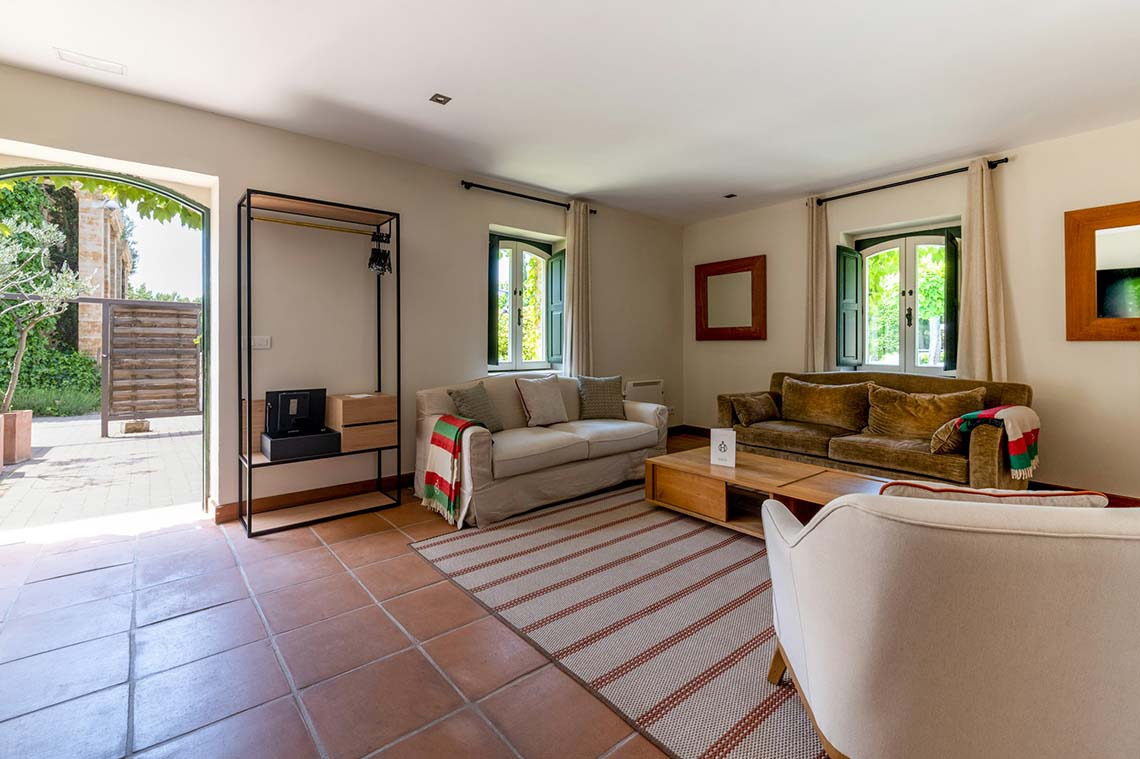 Sala de estar acogedora con sofás, mesa de centro de madera y vista al jardín, ideal para Hacienda Zorita Wine Hotel.