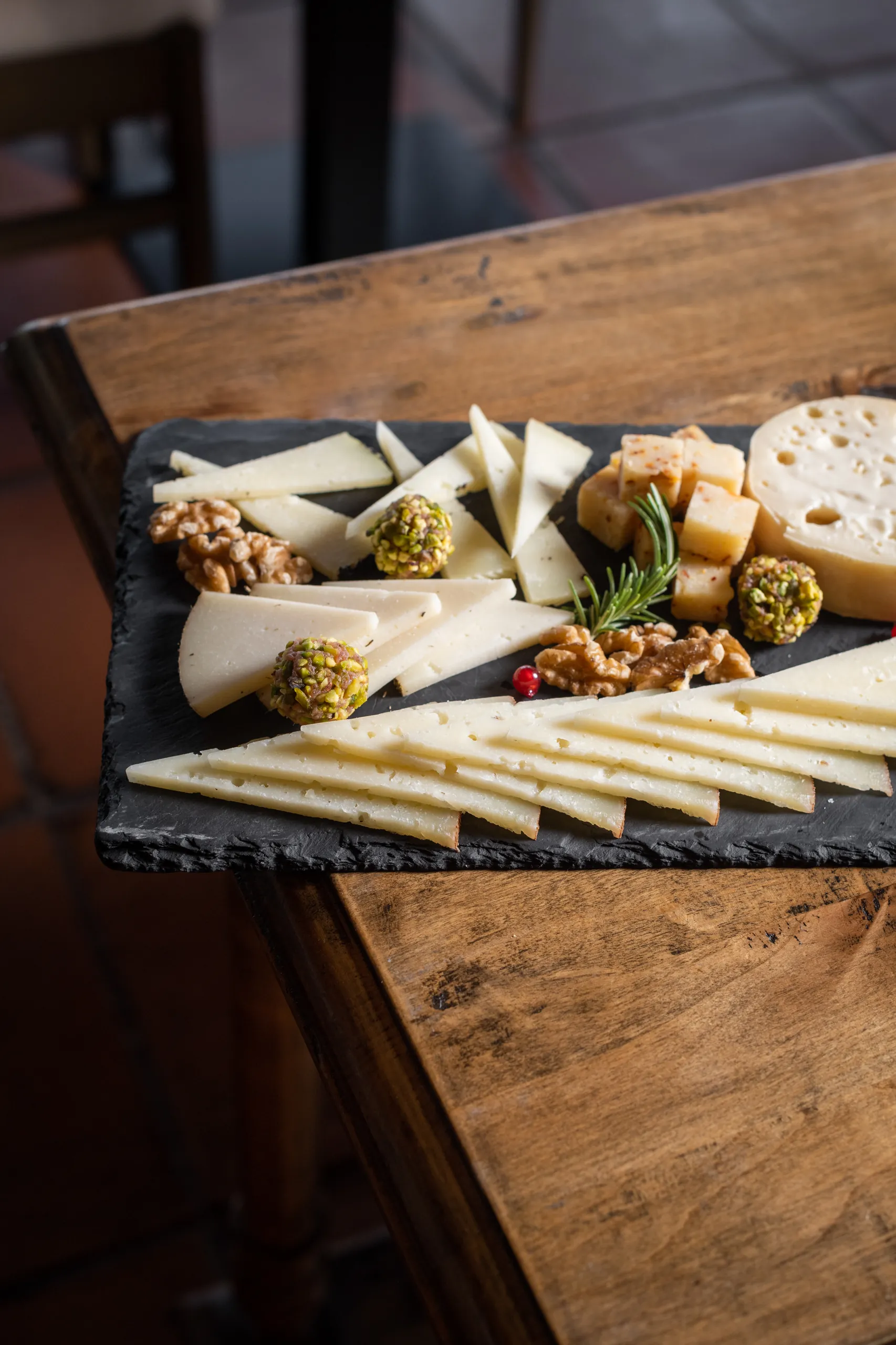 Gourmet cheese board with various cheeses, nuts, and rosemary, perfect for your Hacienda Zorita Wine Hotel experience.