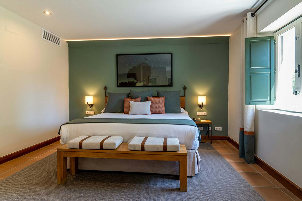 Cama King y ventana con contraventanas en una acogedora habitación de hotel con aire acondicionado Hacienda Zorita Wine Hotel.