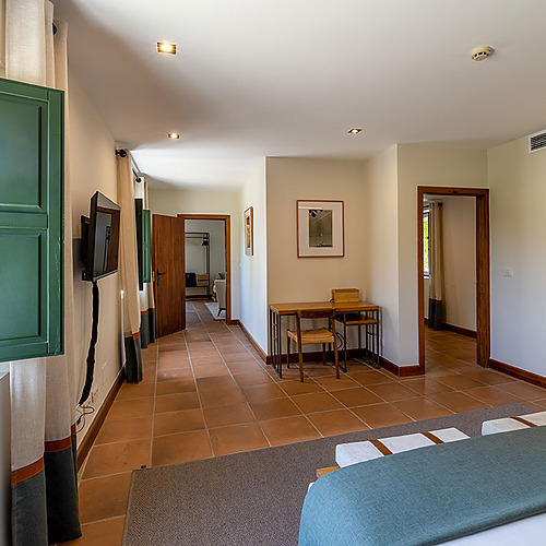 Hacienda Zorita Wine Hotel: dormitorio con persiana verde, escritorio y vista a un pasillo.
