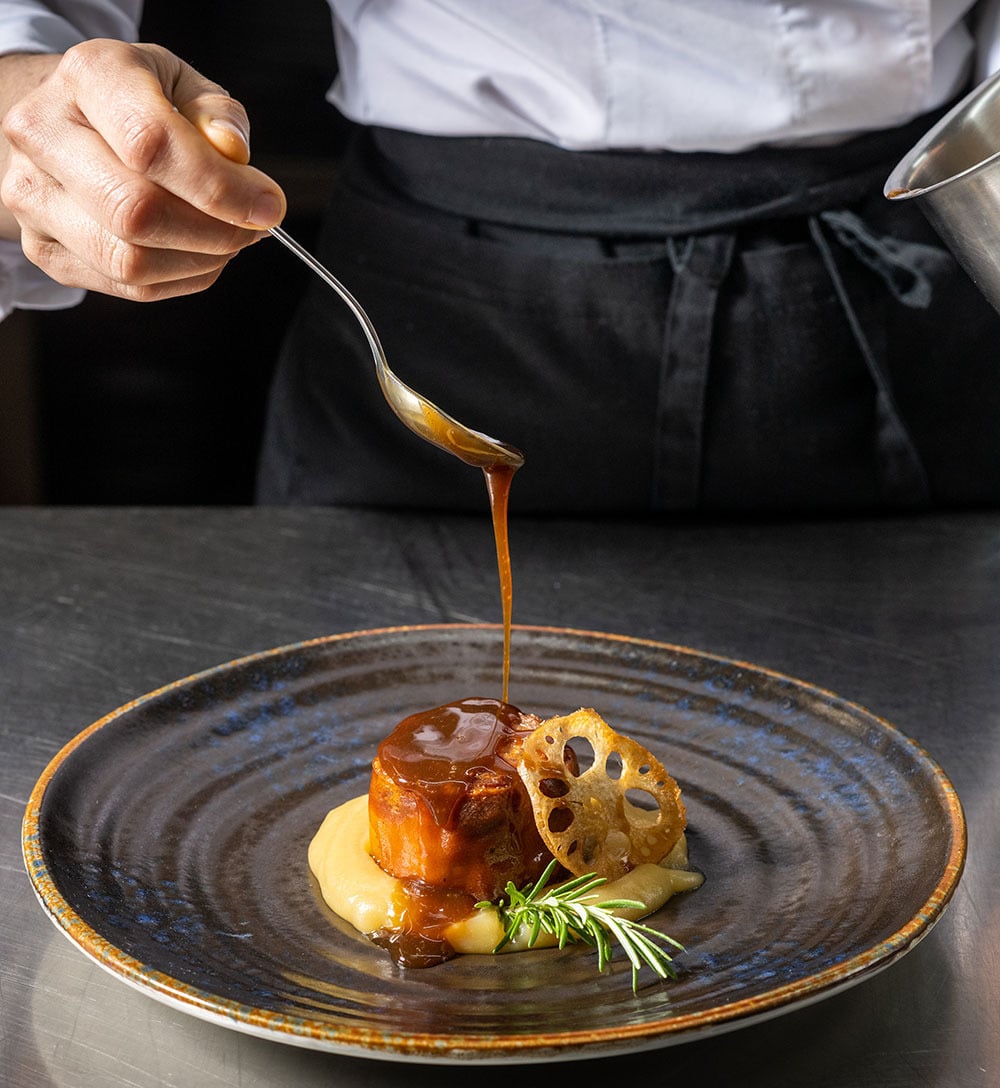Chef glaseando un plato con salsa de caramelo, parte de Hacienda Zorita Wine Hotel.