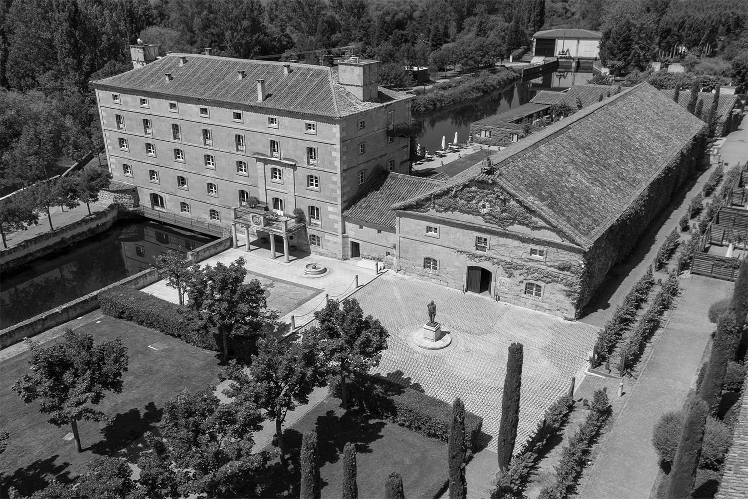 Vista aérea del hotel Hacienda Zorita Wine Hotel, un edificio histórico con canal, jardín y patio con estatua.=s1900