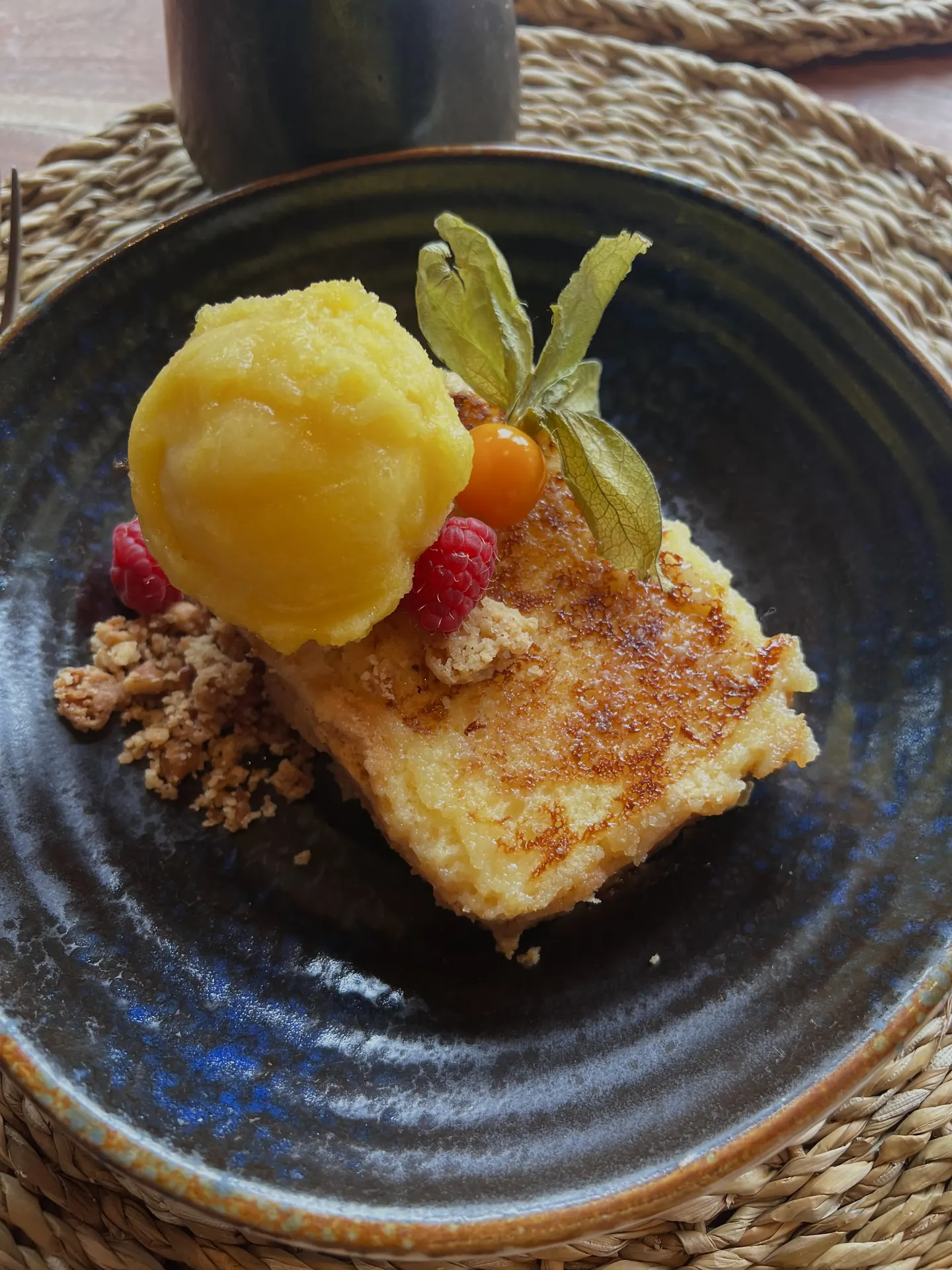 Gourmet dessert with sorbet, raspberry, and physalis on a dark plate, perfect for Hacienda Zorita Wine Hotel.