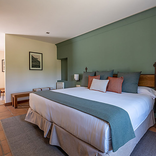 Amplia habitación de hotel con cama king-size, sala y arte: tu Hacienda Zorita Wine Hotel ideal.