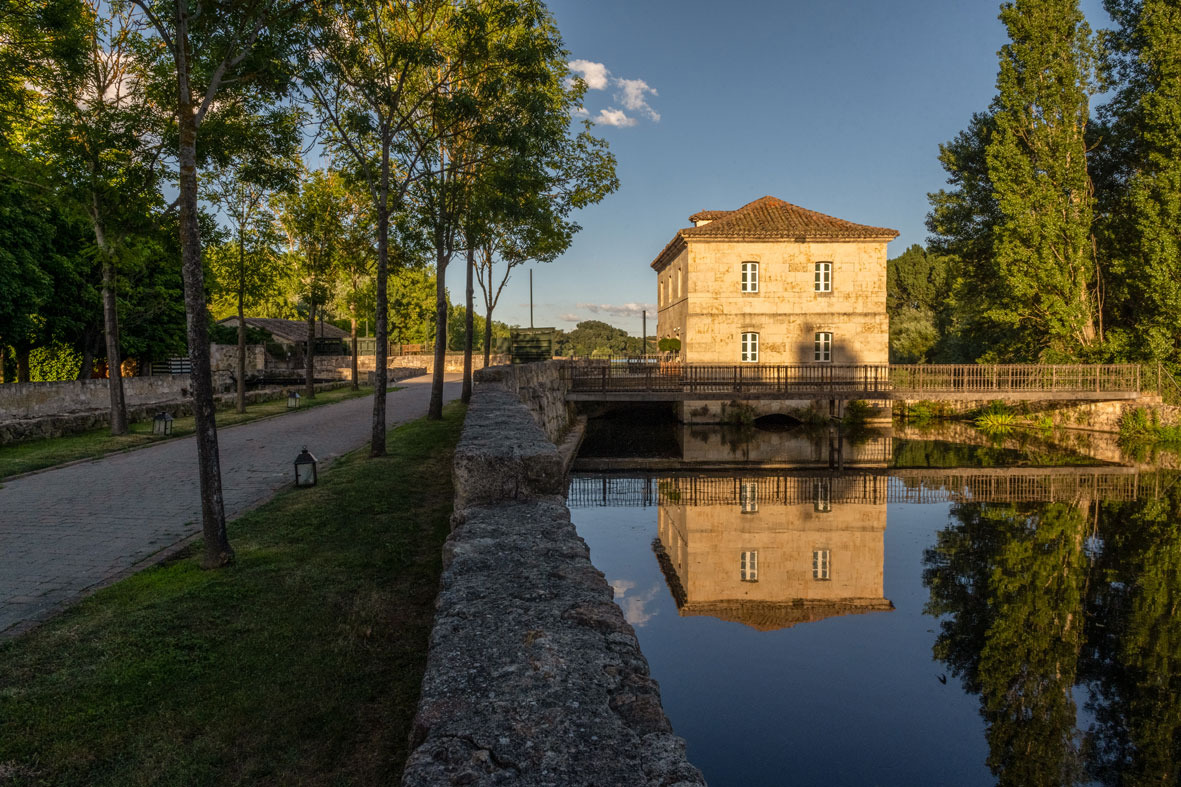 Historic stone building with a bridge over a reflective river, a perfect Hacienda Zorita Wine Hotel escape.