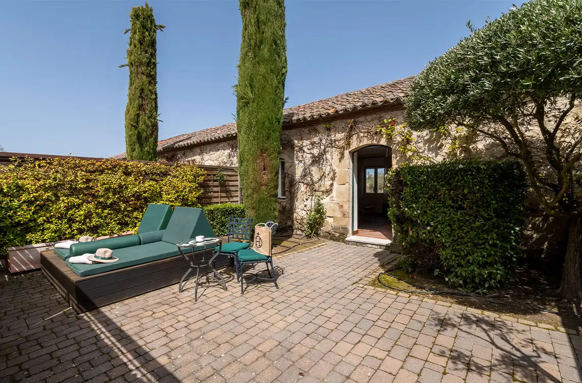 Exterior patio with loungers, chairs, and a stone building, perfect for Hacienda Zorita Wine Hotel.