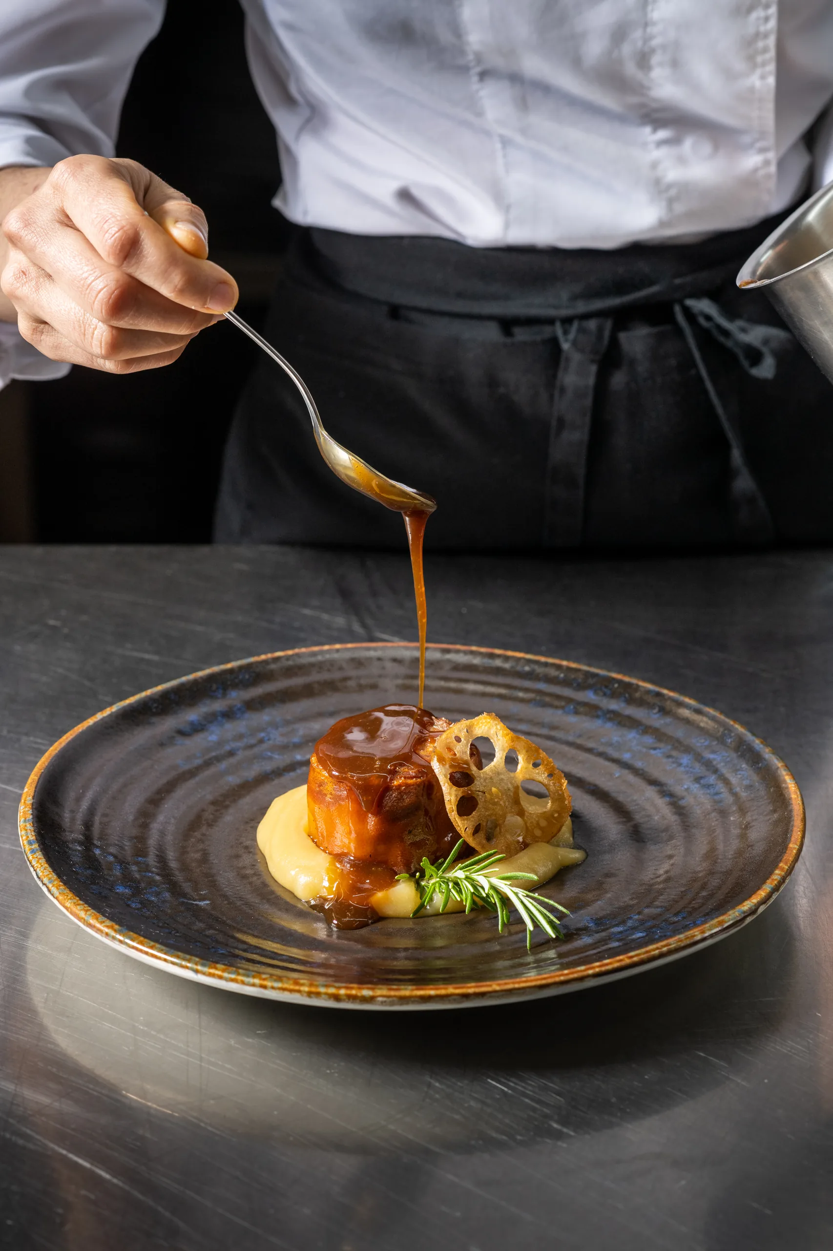 Chef garnishing a gourmet meal with sauce, perfect for Hacienda Zorita Wine Hotel.