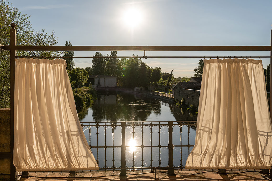 Hacienda Zorita Wine Hotel: Cortinas blancas sobre balcón con vistas al río y edificios históricos.