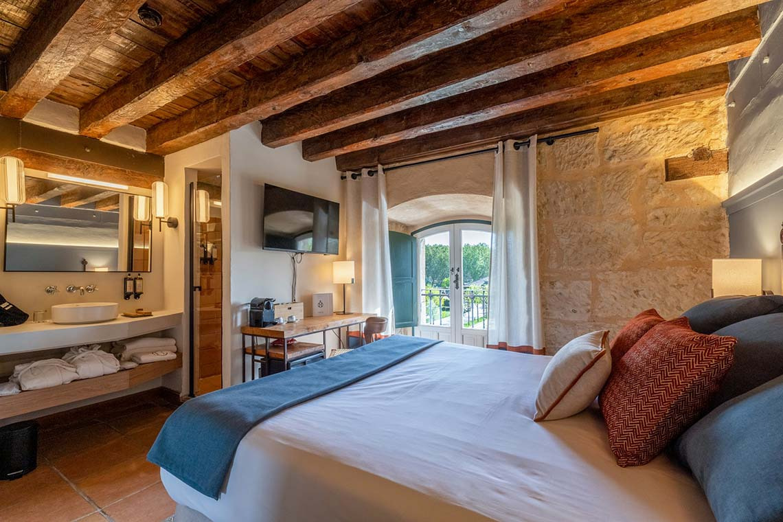 Habitación de lujo con vigas de madera, baño y balcón. Hacienda Zorita Wine Hotel