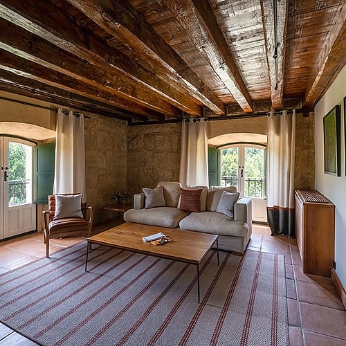Acogedora sala de estar con vigas de madera, sofá cómodo y vistas a Hacienda Zorita Wine Hotel.