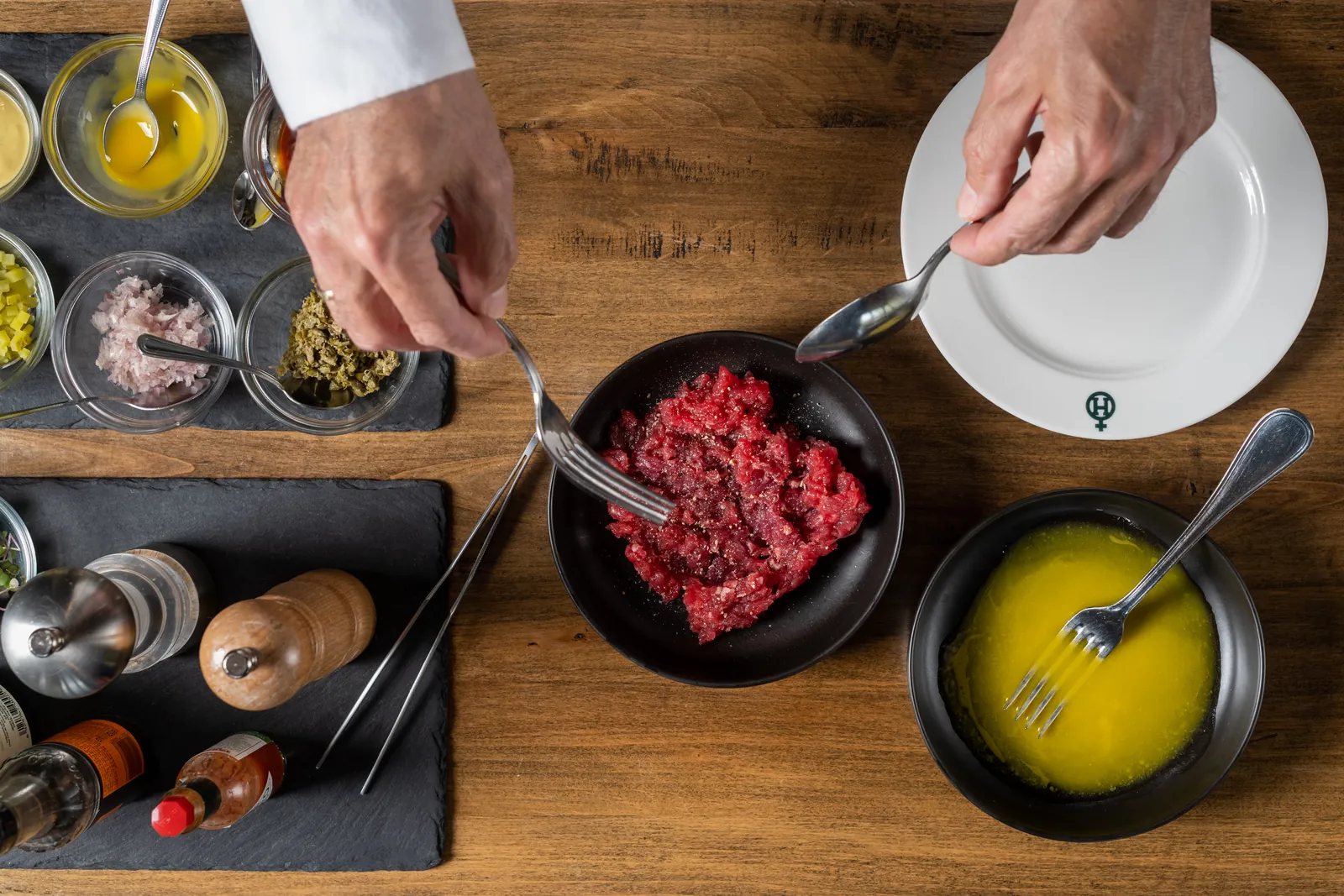 Chef preparing steak tartare with classic condiments and Hacienda Zorita Wine Hotel.