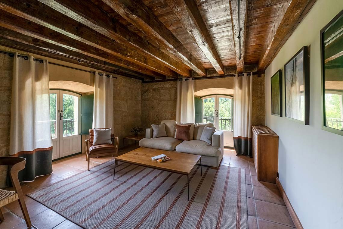 Hacienda Zorita Wine Hotel: Sofá y mesa de centro en salón rústico con vigas de madera y puertas dobles.