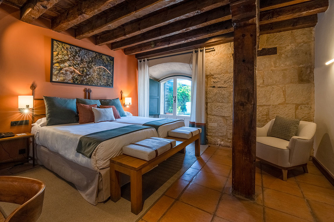 Cómoda habitación de hotel con cama, escritorio y balcón. Hacienda Zorita Wine Hotel