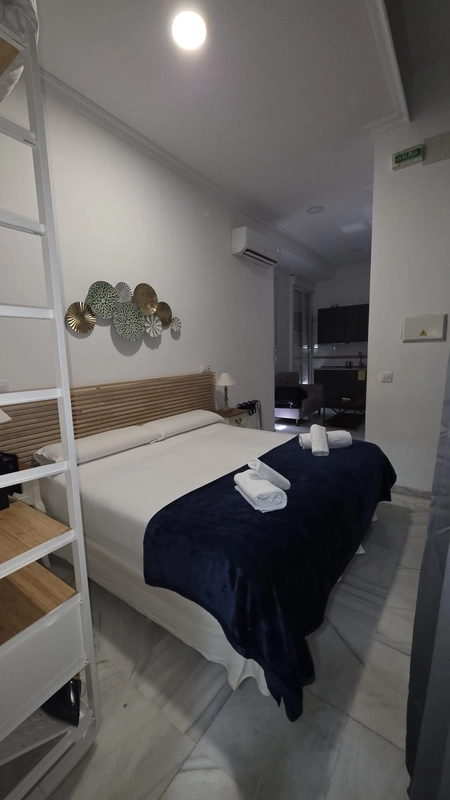Habitación HEMD: Corpo con dos camas, cuadros abstractos y vista a cocina.