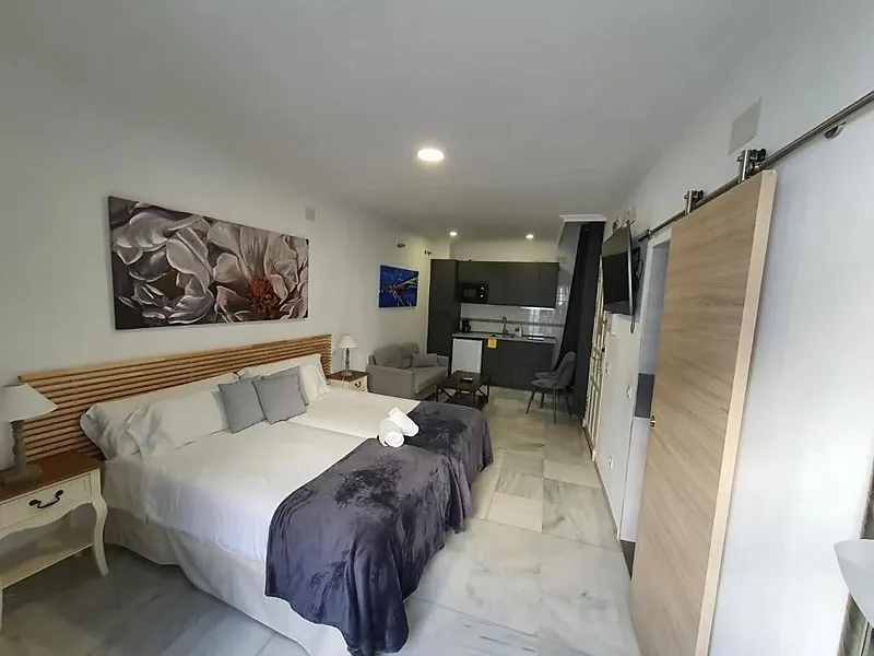 HEMD: Modern living area with sofa, TV, and balcony in hotel.