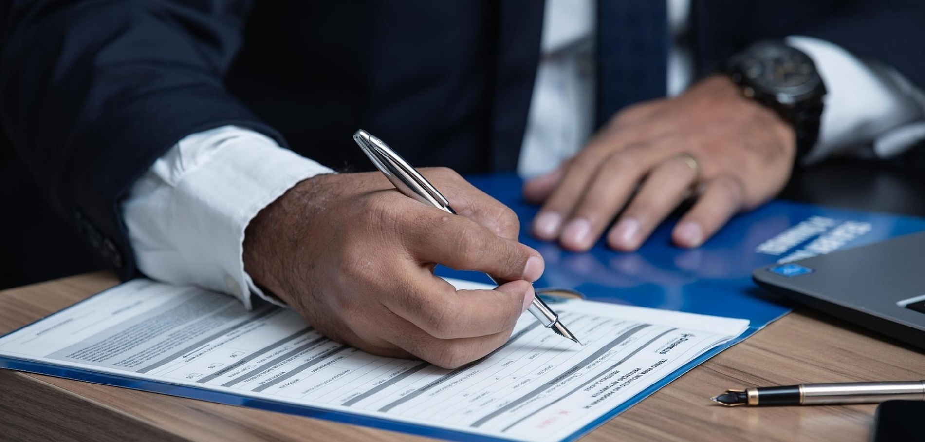un hombre está firmando un documento con un bolígrafo