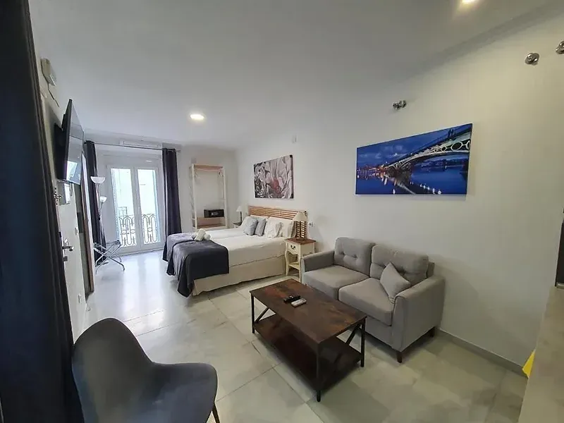 HEMD: Modern living area with sofa, TV, and balcony in hotel.