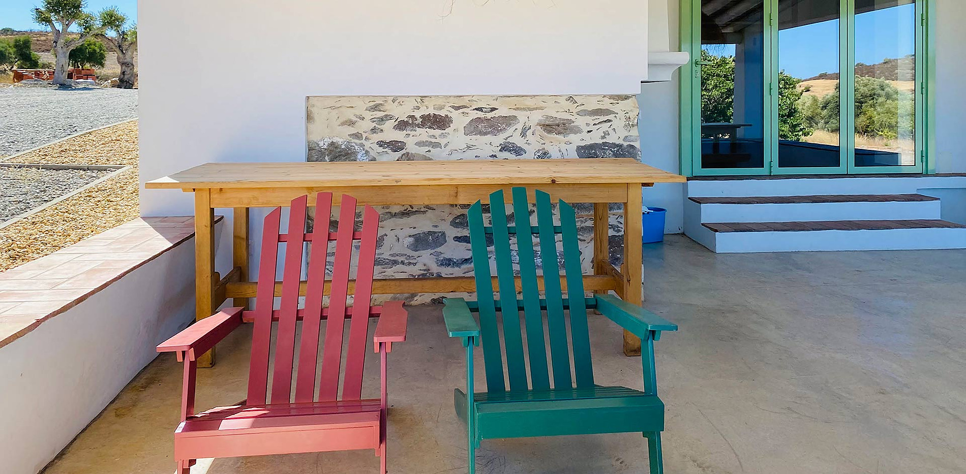 Cadeiras de pátio coloridas em frente a uma mesa de madeira em um hotel Horta de Bufenha.