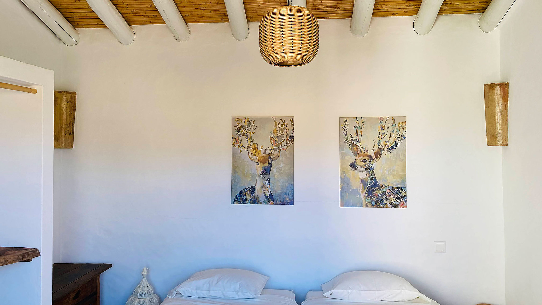 Quartos de hotel com arte de cervos, @Horta de Bufenha@ iluminação natural e teto de madeira rústica.