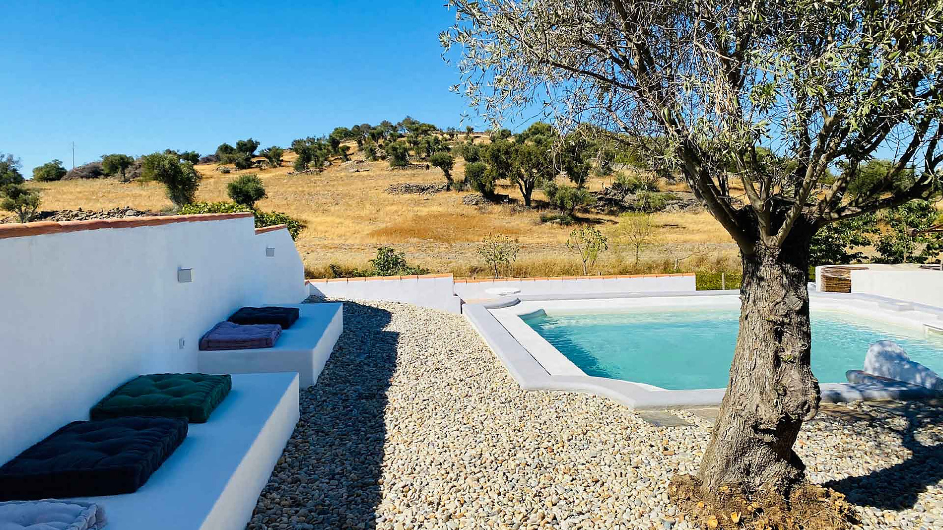 Piscina azul e área de descanso com almofadas em hotel rural, ideal para Horta de Bufenha.