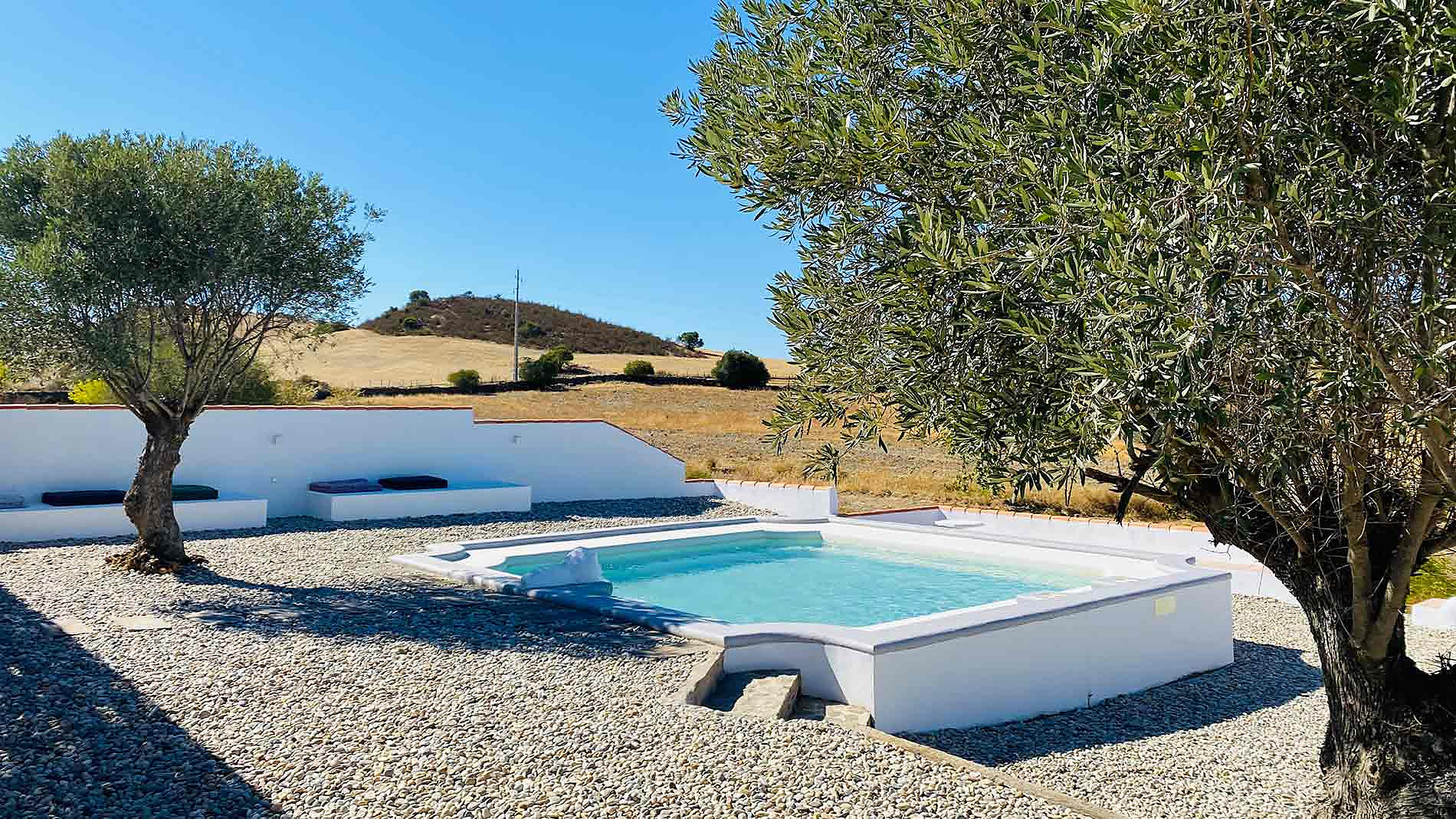 Piscina e área de descanso em hotel rural com Horta da Bufenha, rodeada por oliveiras e paisagem ensolarada.