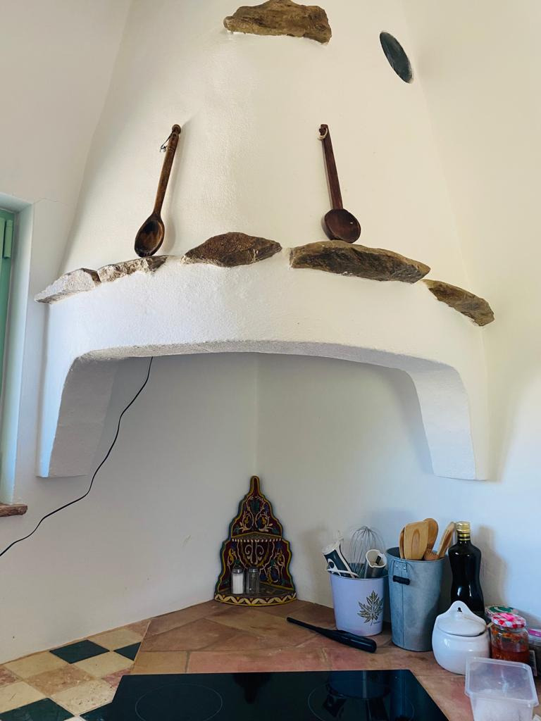 Cozinha rústica com colheres de pau, utensílios e garrafa de azeite. Horta de Bufenha