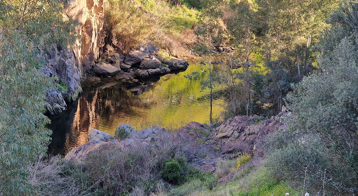 Rio sereno rodeado por rochas e vegetação, ideal paraHorta de Bufenha