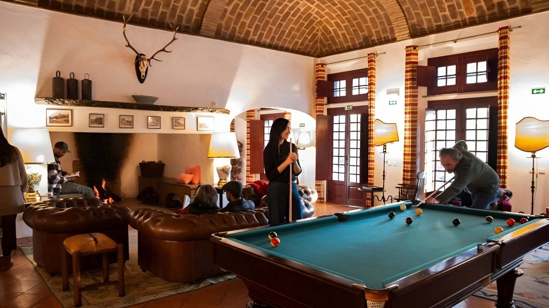 Sala de estar aconchegante na Horta da Moura com lareira, sofás e mesa de bilhar.
